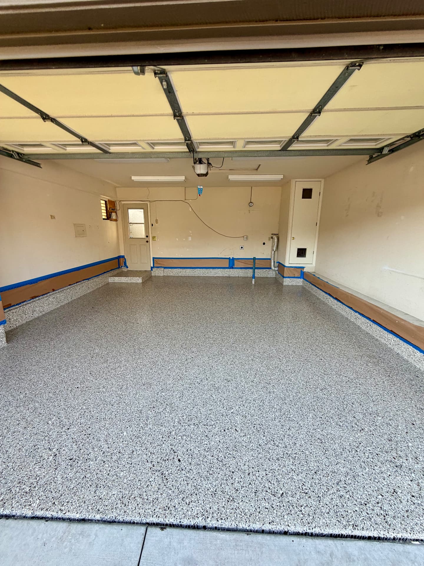 One-Car Flake Garage — Diamond-ground slab, 100% solids base, full-broadcast 1/4" gray and white flake blend, polyaspartic clear top coat